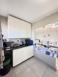 a kitchen with white cabinets and a bed in a room at Lilies & Leopards B&B in Mossel Bay +35 photos