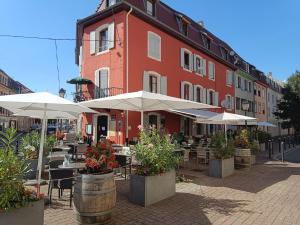 a restaurant with tables and umbrellas in front of a building at Charming guest suite in triborder area in Huningue
