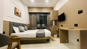 a bedroom with a bed and a desk and a television at Hotel Leaf inn in Ahmedabad