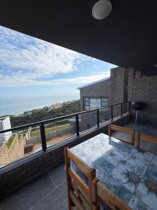 a balcony with a table and a view of the ocean at Lilies & Leopards B&B in Mossel Bay