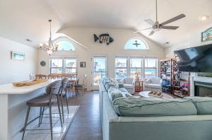 a living room and kitchen with a couch and a table at On The Beach - Kitty Hawk, MP 1, Less than 50 Yards to Beach, Ocean View, Pool, Hot Tub, Pets OK in Kitty Hawk