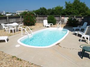 a swimming pool with chairs and a table and chairs at On The Beach - Kitty Hawk, MP 1, Less than 50 Yards to Beach, Ocean View, Pool, Hot Tub, Pets OK in Kitty Hawk