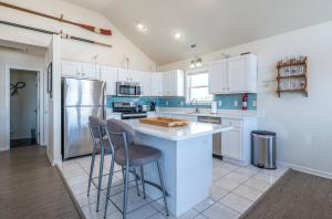 a kitchen with white cabinets and bar stools at On The Beach - Kitty Hawk, MP 1, Less than 50 Yards to Beach, Ocean View, Pool, Hot Tub, Pets OK in Kitty Hawk