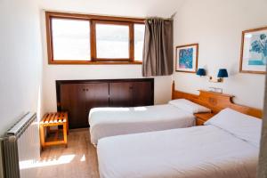 a room with three beds and a window at Apartamentos SNÖ Edelweiss in Cerler