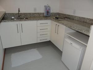 a kitchen with white cabinets and a granite counter top at Residence Flat Prime Itaboraí in Itaboraí