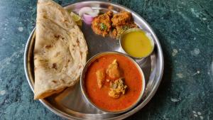 a plate of food with a bowl of soup and a tortilla at Blue Mountain Resorts in Lavasa