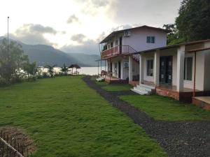 a house with a large yard next to the water at Blue Mountain Resorts in Lavasa