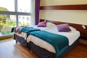 two twin beds in a room with a window at Hotel Ker Vennaik in Bénodet