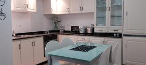 a kitchen with white cabinets and a blue table at Solerma in Viveiro