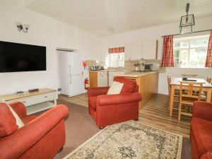 a living room with red furniture and a kitchen at Cottage 3 in Keswick