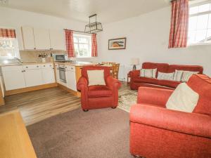 a living room with two red chairs and a kitchen at Cottage 3 in Keswick