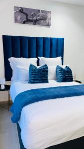 a large bed with blue and white sheets and pillows at Fourways Luxury Residence in Four Ways +45 photos