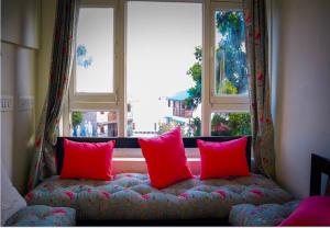a couch with two red pillows in front of a window at help hostel in Mussoorie