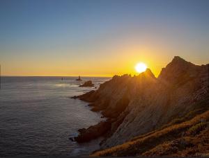 a sun setting over the ocean on a rocky coast at Chambre confortable chez Isabelle in Cléden-Cap-Sizun +4 photos