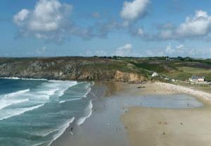 a group of people on a beach near the ocean at Chambre confortable chez Isabelle in Cléden-Cap-Sizun