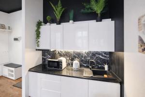 a kitchen with white cabinets and plants on the wall at Apartament Azyl in Przemyśl