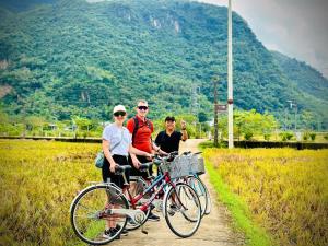 three people standing next to a bike on a path at Mai Chau La Luna in Mai Châu