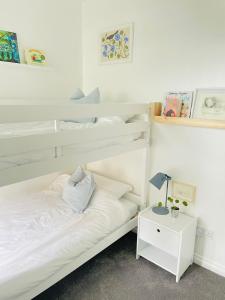 a white bedroom with two bunk beds and a lamp at Beachfront Retreat in Falmouth