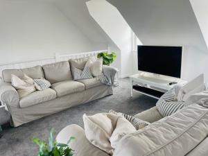 a living room with a couch and a flat screen tv at Beachfront Retreat in Falmouth
