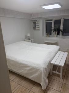 a bedroom with a white bed and a bench at Herregårdslejlighed in Vrå
