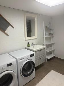 a bathroom with a washing machine and a sink at Herregårdslejlighed in Vrå