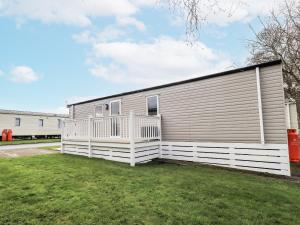 a house with a white fence next to a yard at Hadrian's Rest Glendale Holiday Park in Wigton