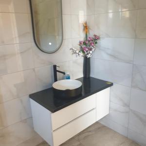 a bathroom with a sink and a vase of flowers at Szabó Vendégház in Bükkszék +8 photos