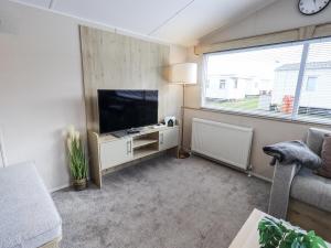 a living room with a flat screen tv and a chair at Hadrian's Rest Glendale Holiday Park in Wigton