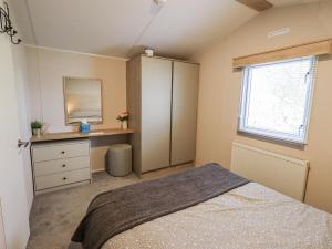 a bedroom with a bed and a dresser and a window at Hadrian's Rest Glendale Holiday Park in Wigton