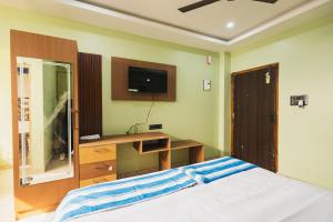 a bedroom with a bed and a desk and a tv at Lotus Leaf GuestHouse in Guwahati