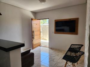 a living room with a television and a chair at Lar de verão casa 01 in Barra de São Miguel