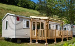a white house with a porch and a deck at Camping U Pezzo - Mobil home 4 pièces 6/8 personnes Climatisé MAE-2285 in Saint-Florent