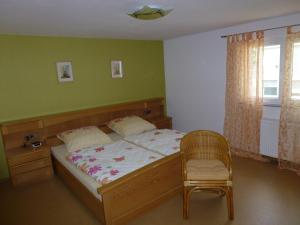 a bedroom with a bed with a chair and a window at Ferienwohnung Neifer in Bad Überkingen +14 photos