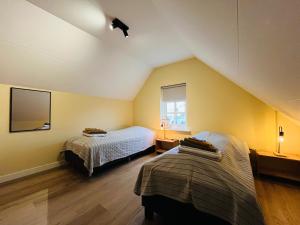 two beds in a room with yellow walls at It Winkelhûs in Terschelling