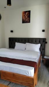 a bedroom with a bed with white sheets and a picture on the wall at Ashe Oleng House in Arusha