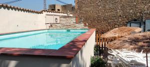a swimming pool with chairs and umbrellas next to a building at Cal Belló in Hostafranco