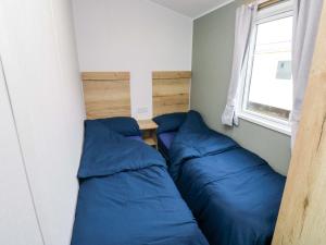 a bedroom with two blue pillows and a window at The Foxy Cobbler in Kingsbridge
