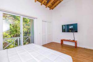 a white bedroom with a bed and a large window at Blue Roatan Resort in West Bay