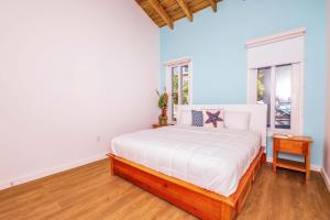 a bedroom with a bed with white sheets and a window at Blue Roatan Resort in West Bay