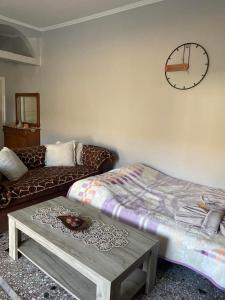 a living room with a bed and a clock on the wall at Eva's house in Xanthi
