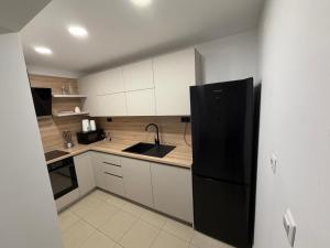 a kitchen with white cabinets and a black refrigerator at Apartments Volarevic in Blace