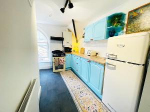 a kitchen with blue cabinets and a white refrigerator at Langdale Loft - Whitby in Whitby