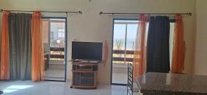 a living room with a television and sliding glass doors at Le tout confort face à la mer in Sidi Ifni