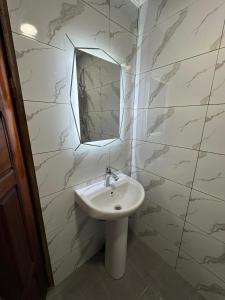 a bathroom with a sink and a mirror at Appartement moderne et épuré in Bonabéri