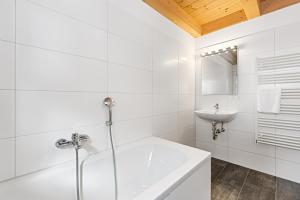a white bathroom with a tub and a sink at Chalet Lachtal in Lachtal