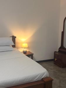 a bedroom with a bed and a lamp on a table at Ancestral Aura in Negombo