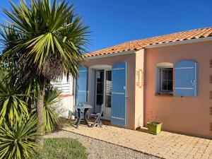 a house with blue doors and a palm tree at La Dyva 2 in Saint-Jean-de-Monts