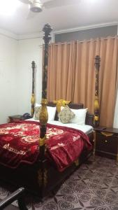 a bedroom with a bed with a red comforter at Green View Inn Hotel in Lahore