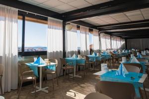 ein Restaurant mit blauen Tischen, Stühlen und Fenstern in der Unterkunft Cav Approdo in Castiglione della Pescaia