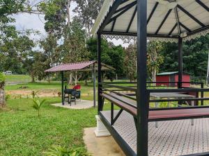 a park with a bench and a gazebo at Singgah Dusun Zahra in Kampong Perak +3 photos